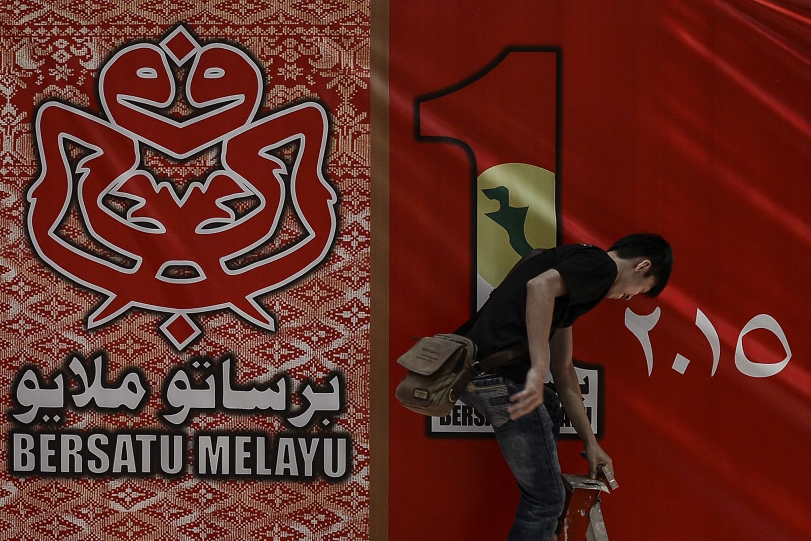 A worker makes the final touches to a signboard welcoming delegates to the Umno general assembly at the Putra World Trade Centre. The son of the late Tun Dr Ismail Abdul Rahman says Umno is no longer a party of ideas, but a patronage machine for businessmen. – The Malaysian Insider pic by Nazir Sufari, December 7, 2015.